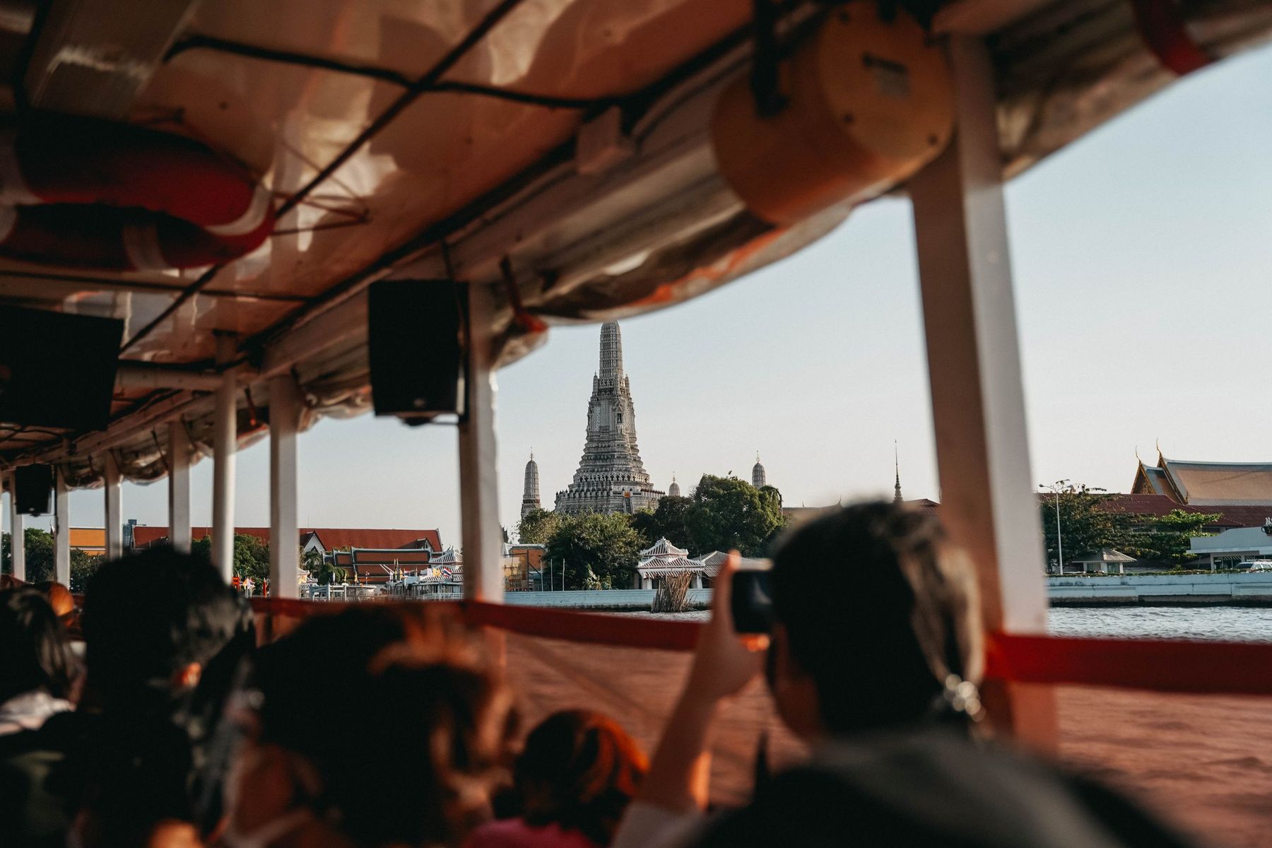 Wat Arun seen from inside a riverboat on the Chao Phraya, with passengers in the foreground