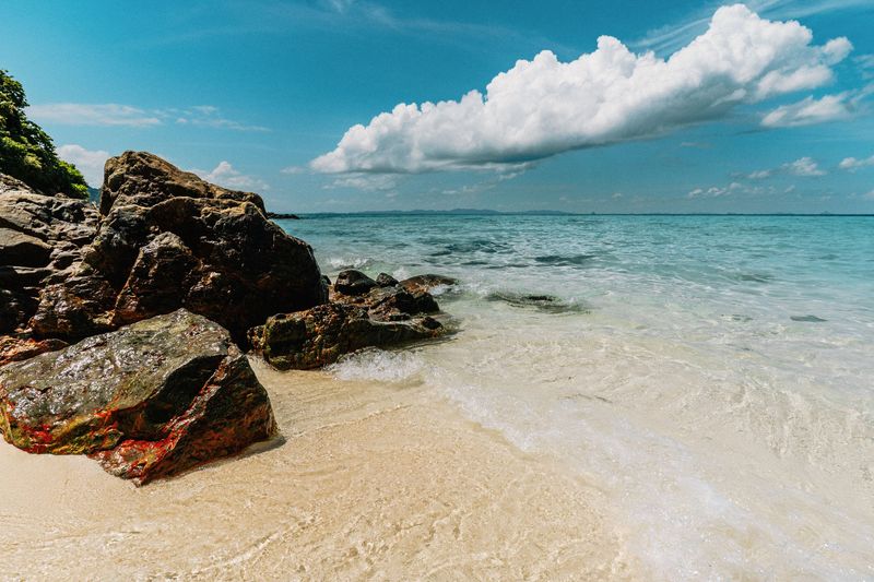 Rocks scattered across a white sand beach with clear water