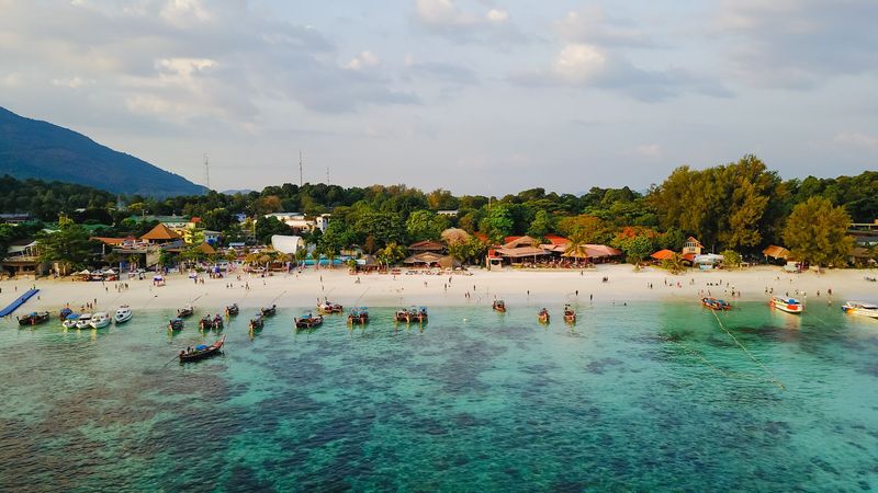 Aerial view of a tropical beach with boats and green hills