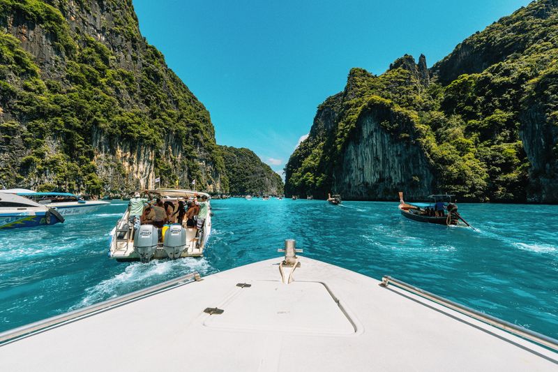 The bow of a tour boat heading between limestone cliffs