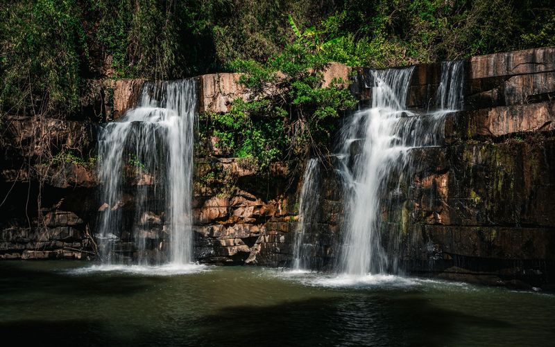 A waterfall falling over rocks into a pool in lush forest