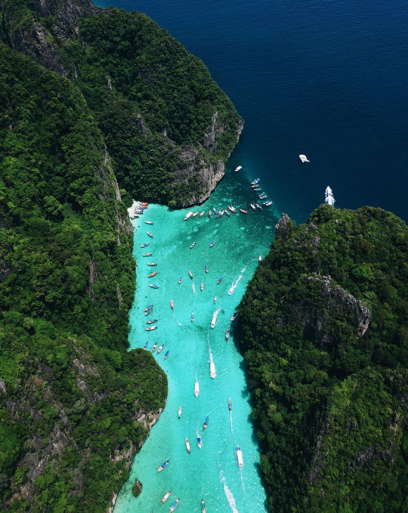A turquoise lagoon between jungle-covered limestone walls, seen from above