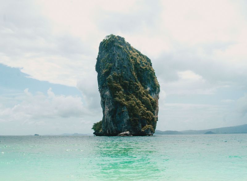 A single limestone pillar rising from clear shallow water