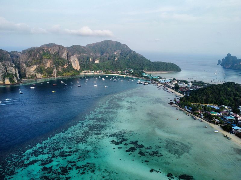 Aerial view of the Phi Phi coast with turquoise shallows and green hills