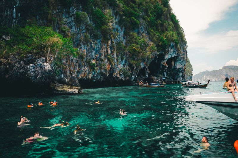 Swimmers in turquoise water near limestone cliffs