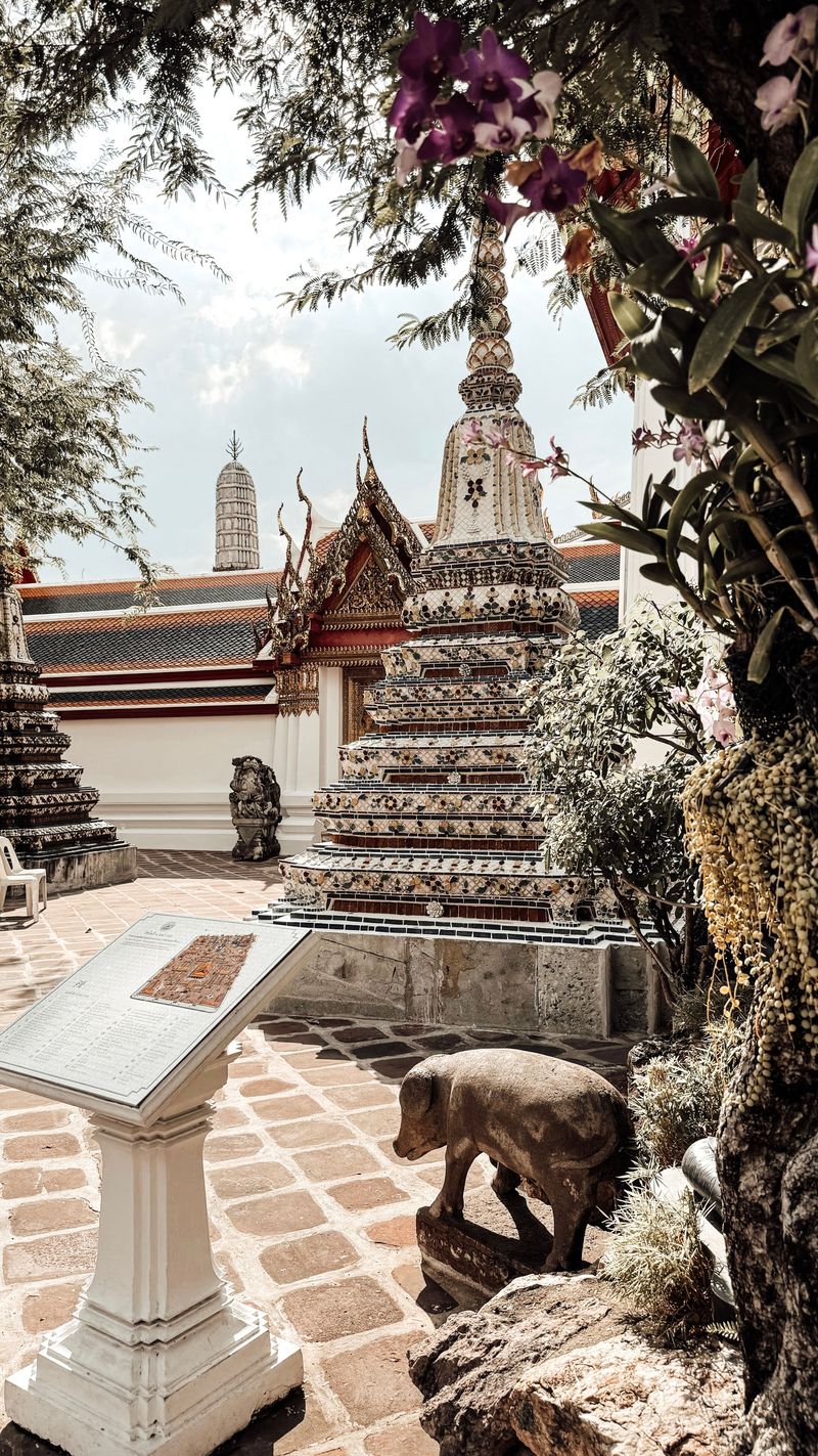 The central spire of Wat Arun, covered in coloured porcelain, with flowers in front