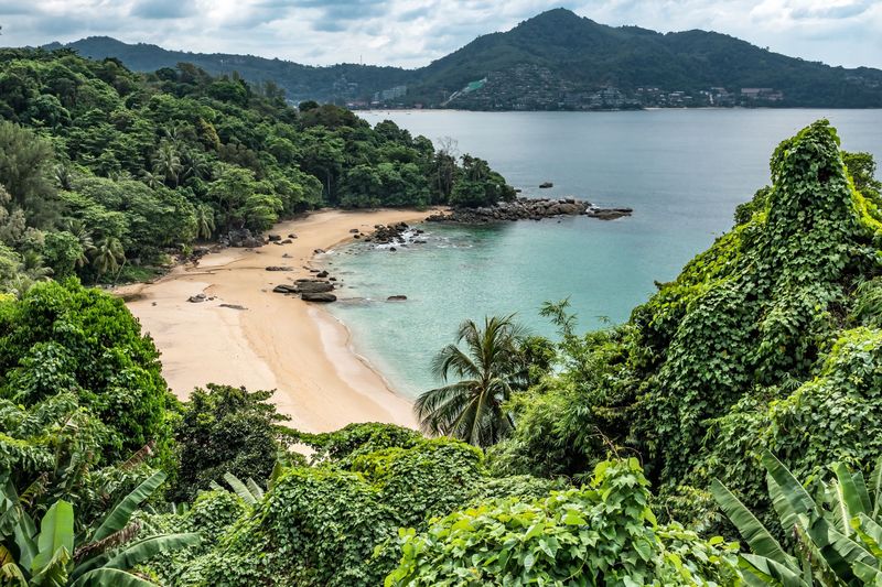 A small beach cove surrounded by green hills in Phuket