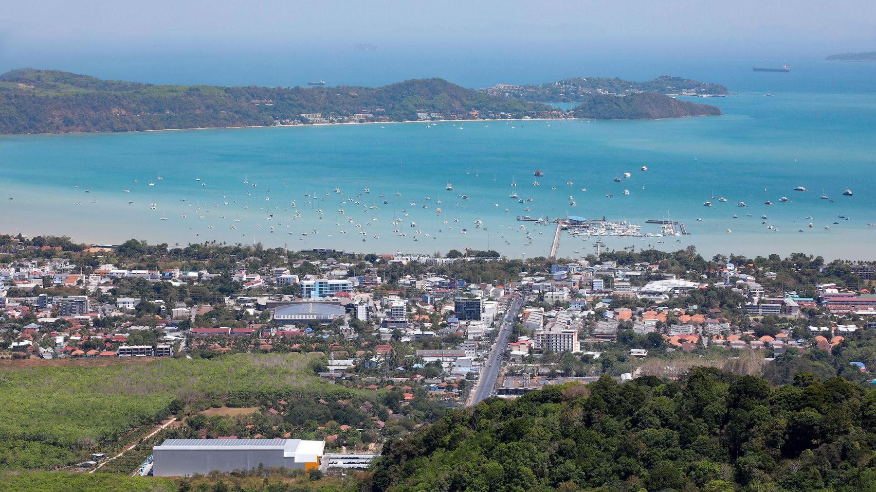 Aerial view of Karon Beach in Phuket, with turquoise water, the town and green hills