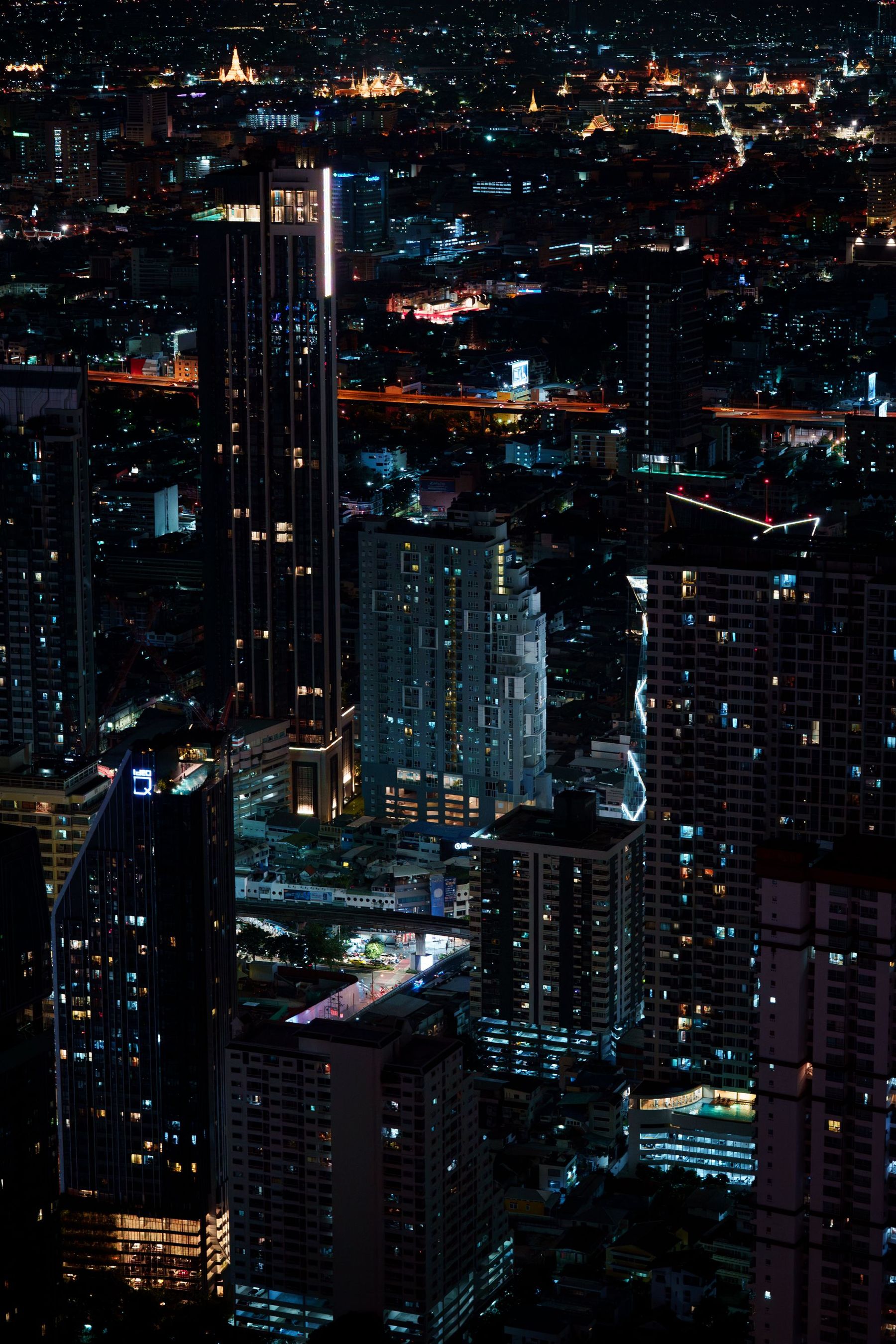 Bangkok's skyscrapers lit up at night above a busy road