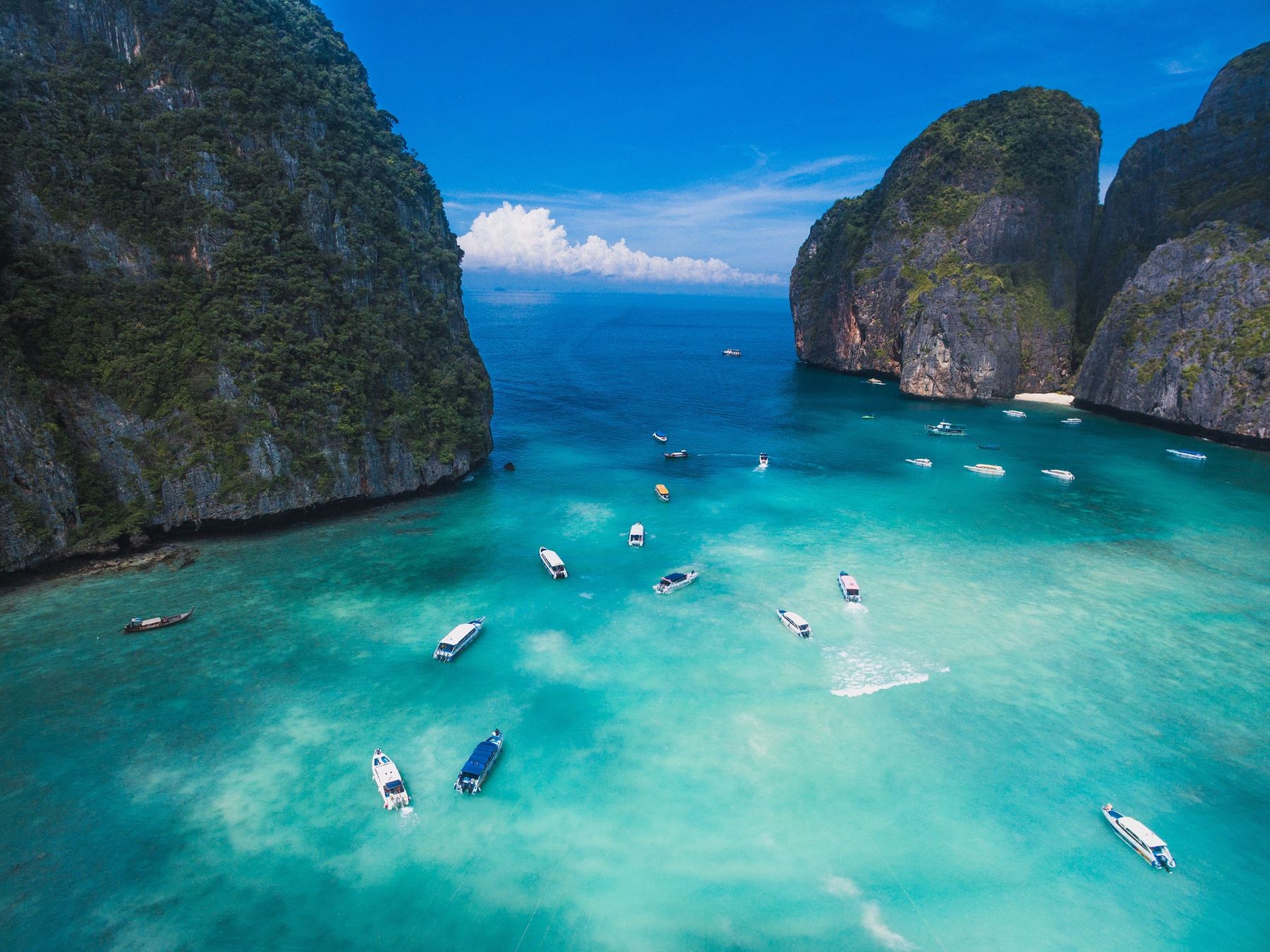 A bay of turquoise water and white sand enclosed by green limestone cliffs